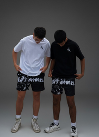Two people wearing black shorts with 'LIFT APPAREL' branding on a gray background.