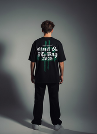 Person wearing a black t-shirt with text on the back against a gray background