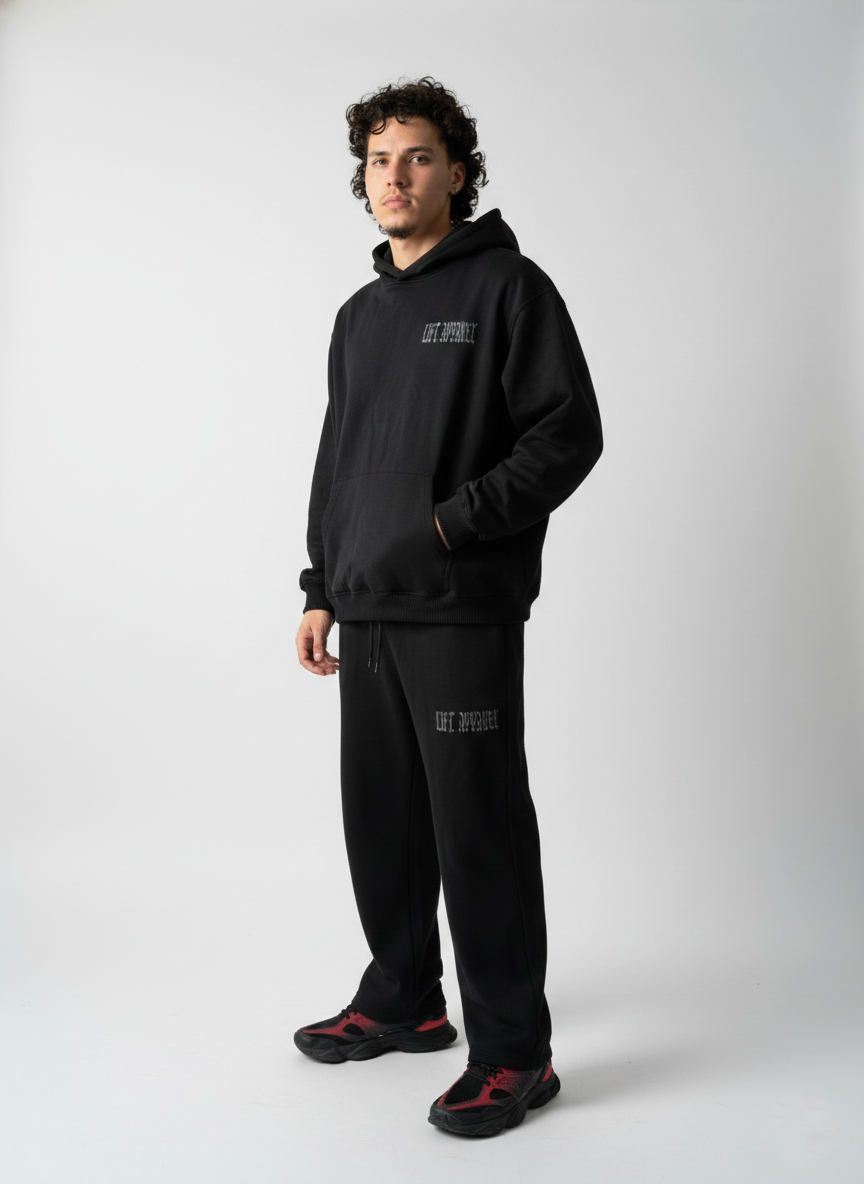 Person wearing a black hoodie and pants with text on a white background