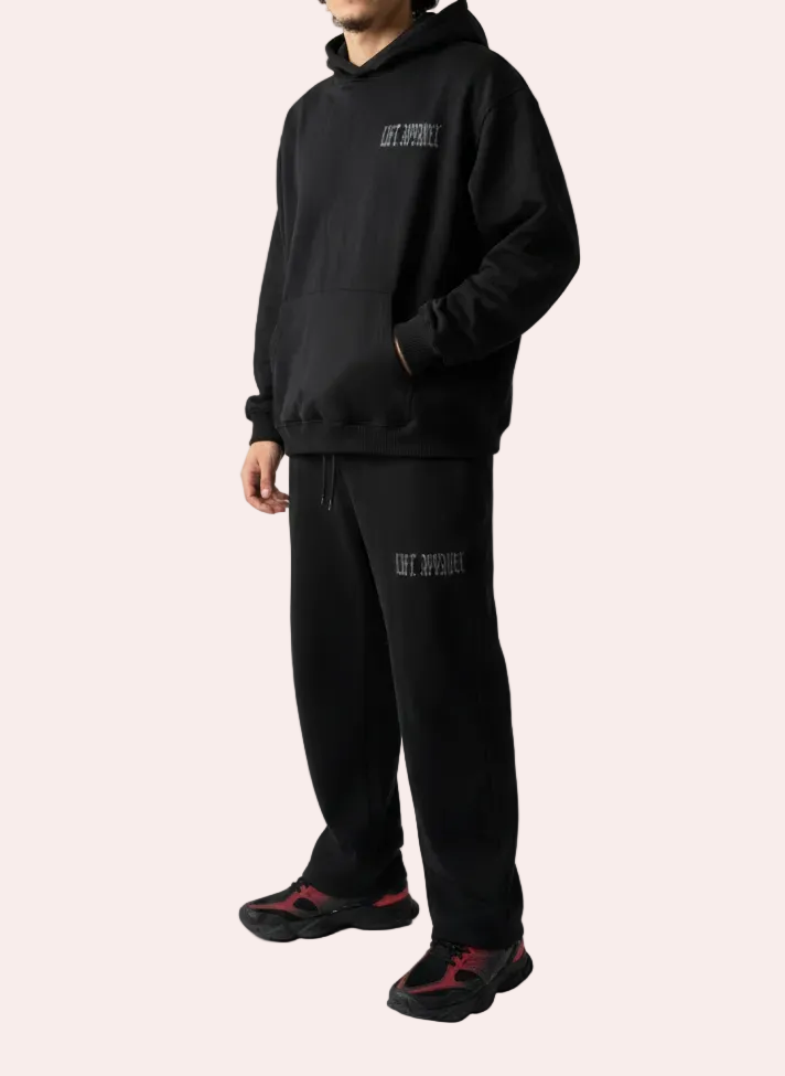 Person wearing a black hoodie and pants with text on a white background