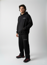 Person wearing a black hoodie and pants with text on a white background