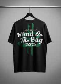 Black t-shirt with white and green text on a hanger against a gray background