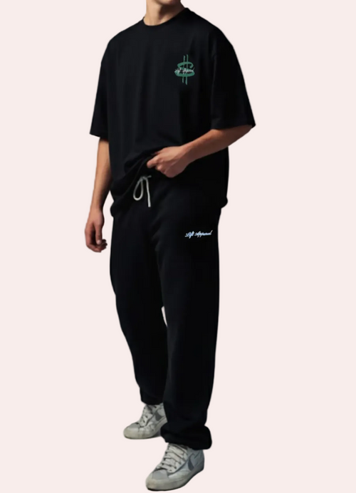 Person wearing a black t-shirt and pants with logos on a gray background