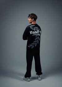 Person wearing a black outfit with text and graphics on the back against a gray background