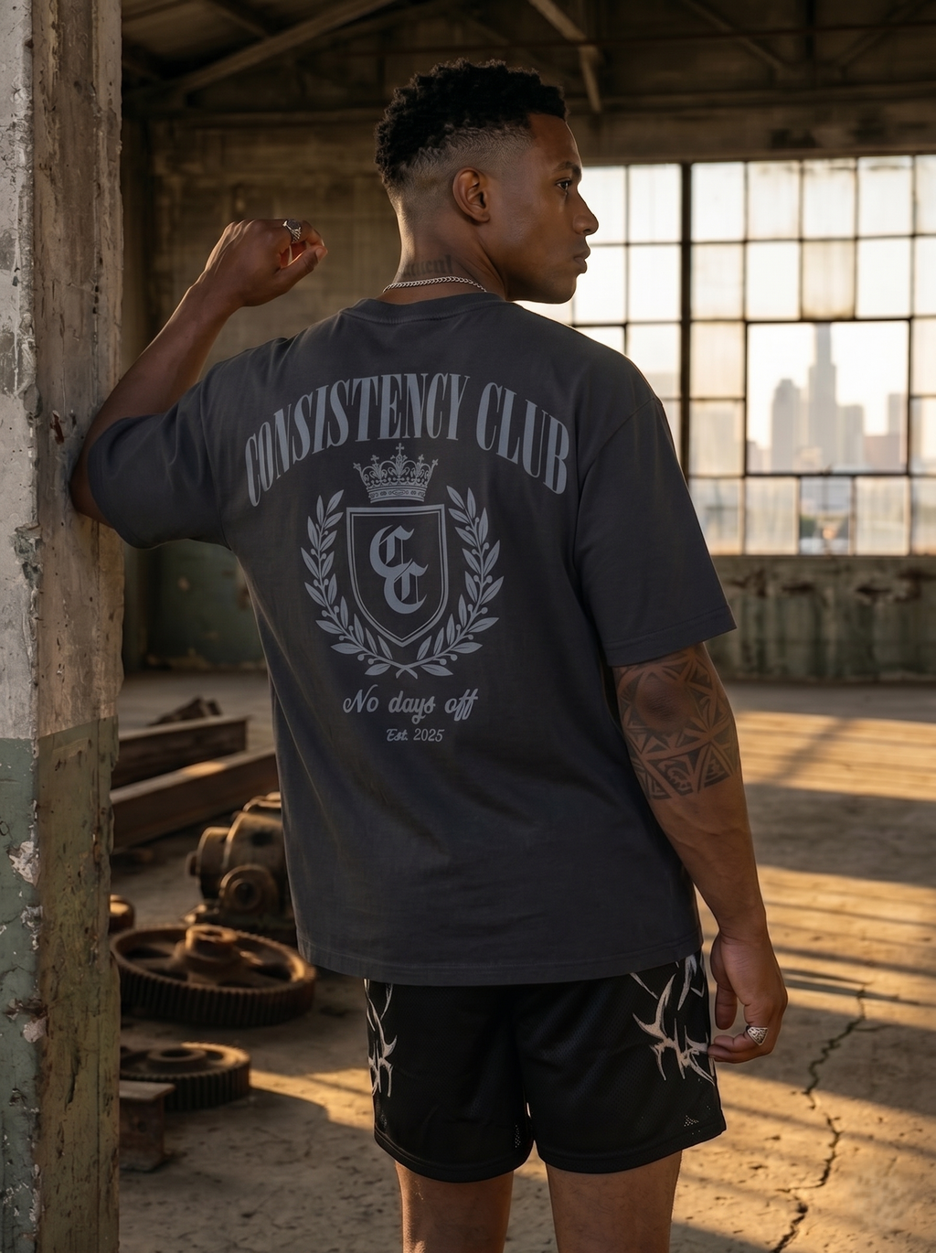 Man wearing a 'Consistency Club' t-shirt in an industrial setting