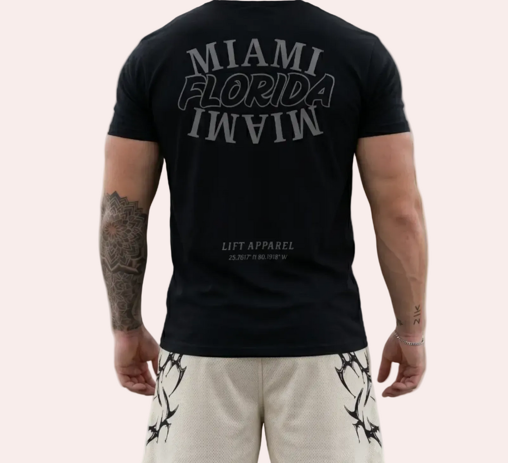 Person wearing a black t-shirt with 'MIAMI FLORIDA IN VIVO' text, standing on an urban street.