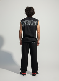 Person wearing a black sleeveless shirt with text on the back against a light gray background