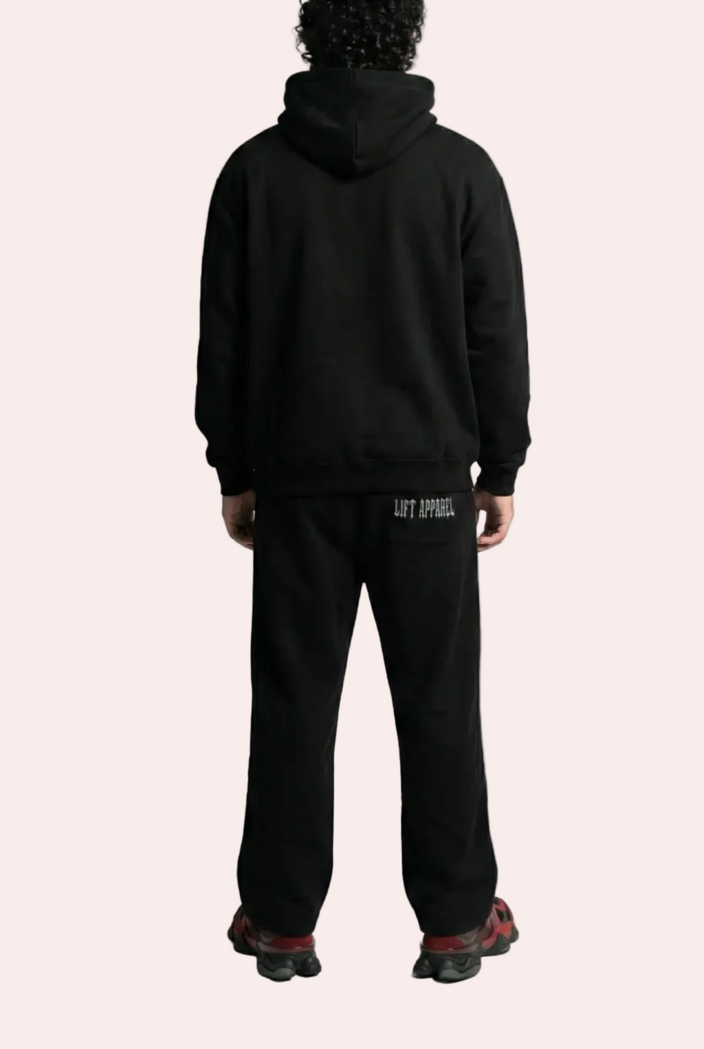 Person wearing a black hoodie and pants on a white background