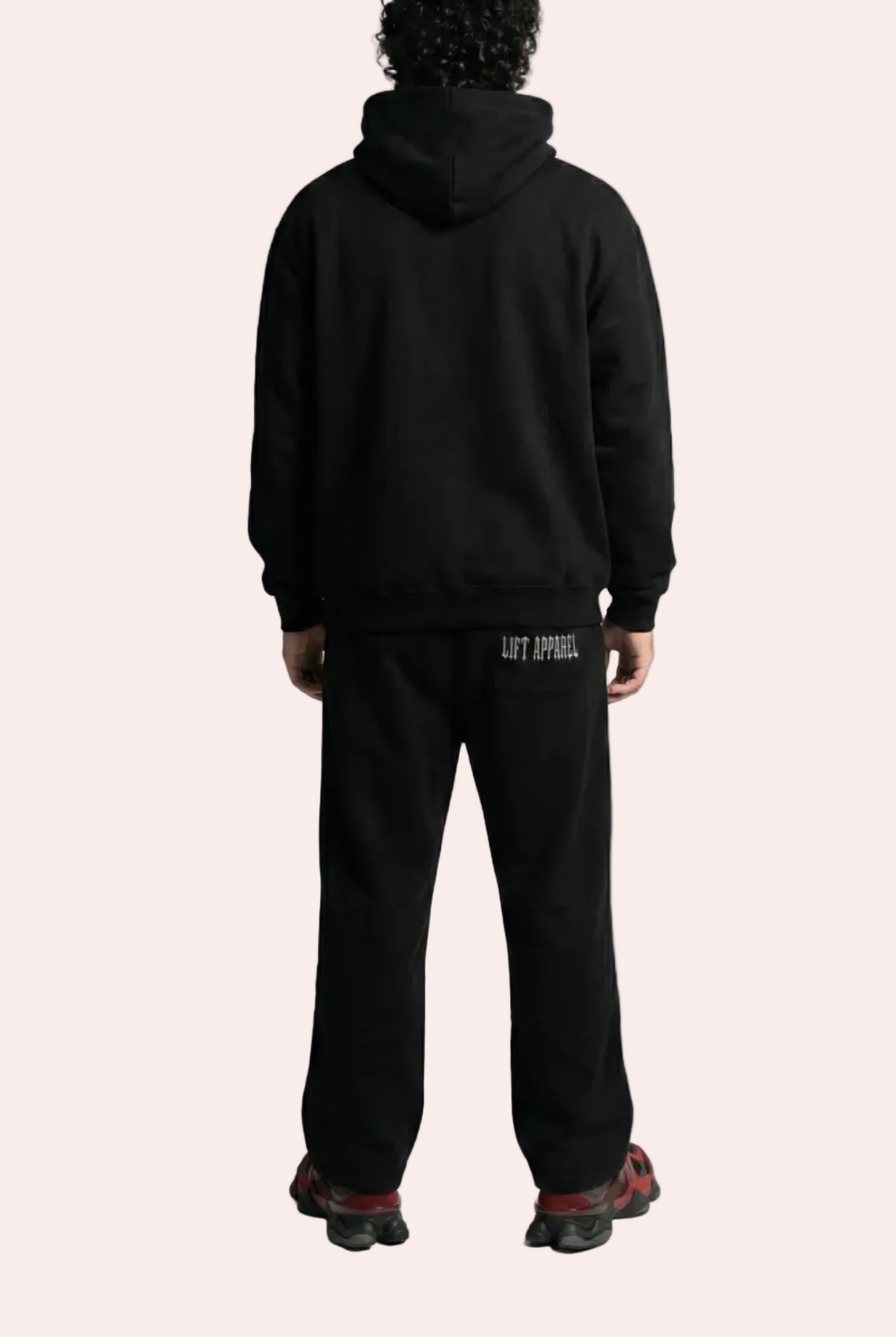 Person wearing a black hoodie and pants on a white background