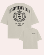 Beige t-shirt with 'Consistency Club' design on a white background
