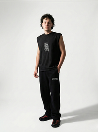 Person wearing a black sleeveless shirt and pants with logos on a white background
