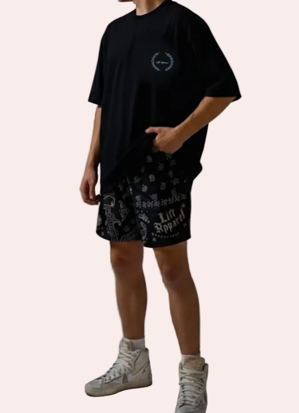 Person wearing a black t-shirt and patterned shorts on a gray background