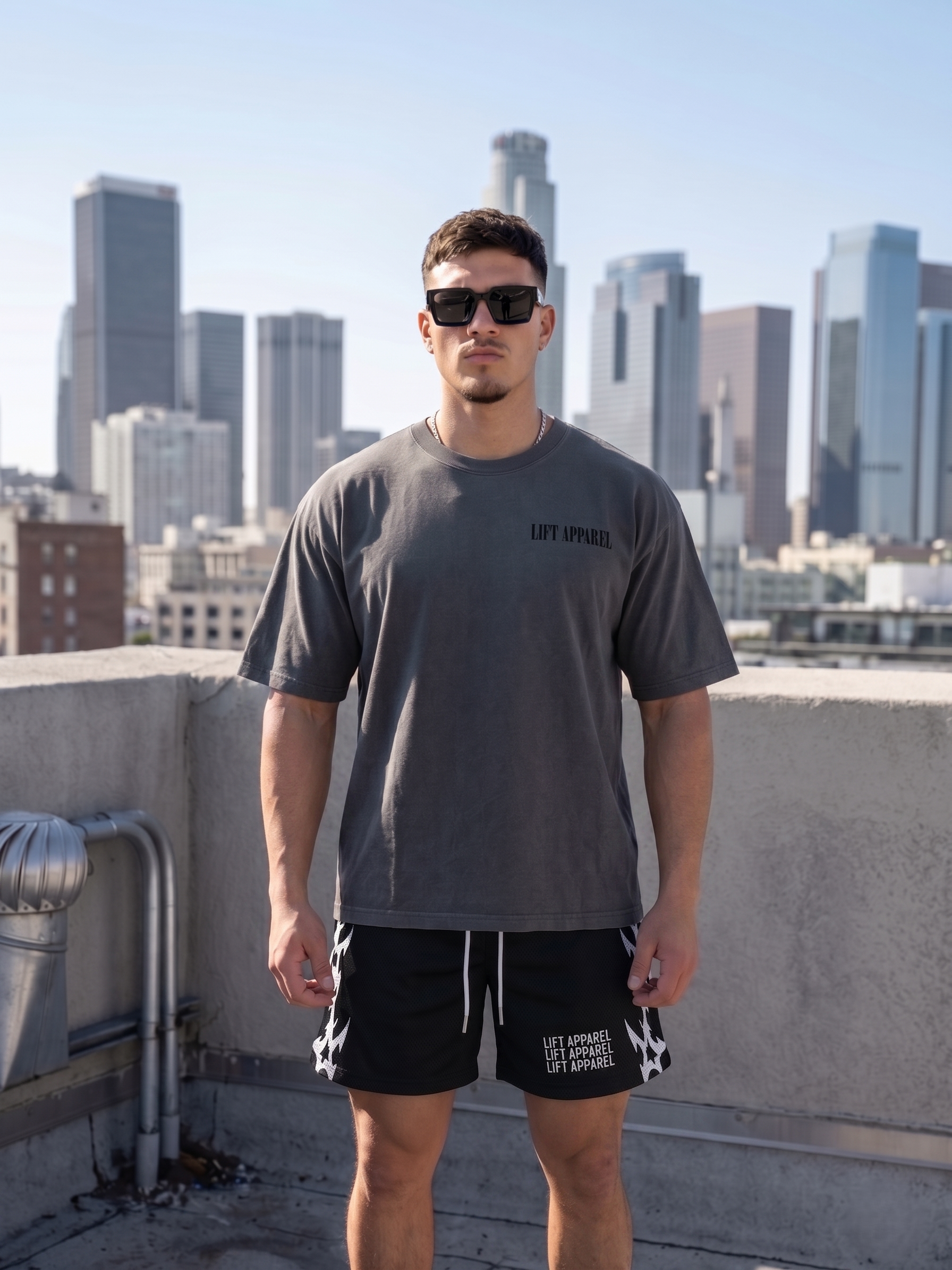 Man wearing sunglasses and a gray t-shirt with a city skyline in the background