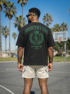 Man wearing a black 'Consistency Club' t-shirt on a basketball court with palm trees in the background