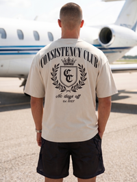 Person wearing a 'Consistency Club' t-shirt with an airplane in the background