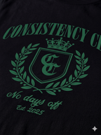 Black shirt with green 'Consistency Club' logo and text on a dark background