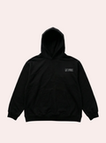 Black hoodie with a small logo on the chest against a gray background