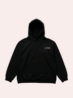 Black hoodie with a small logo on the chest against a gray background