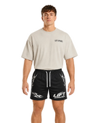 Man wearing black Apex gym shorts with white tribal print and a cream oversized tee, front view