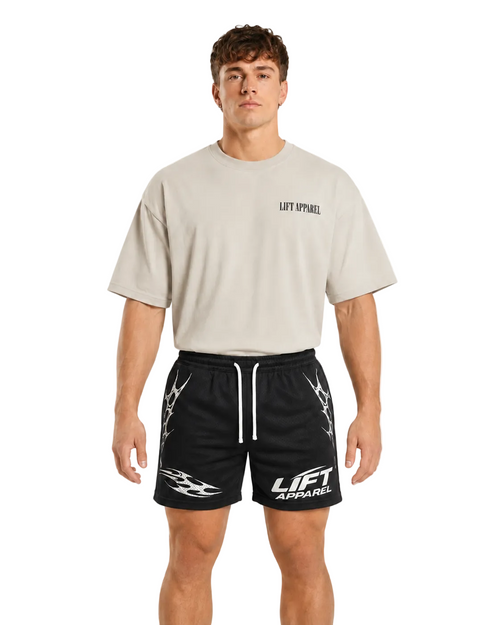 Man wearing black Apex gym shorts with white tribal print and a cream oversized tee, front view