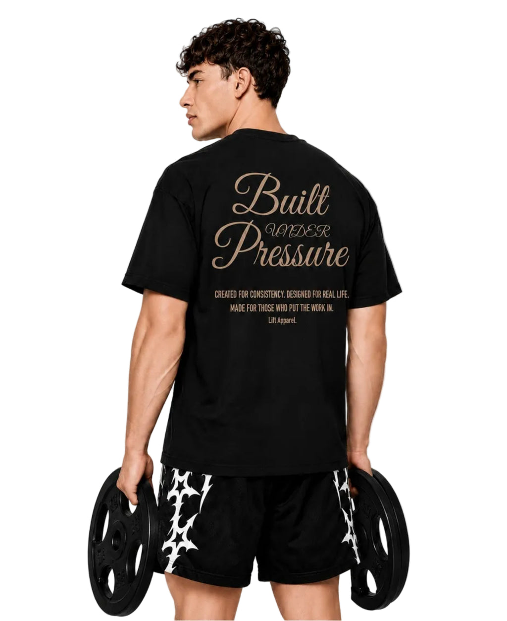 Man holding weight plates, back view of the black Pressure tee with gold script print