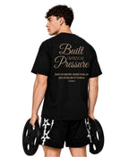 Man holding weight plates, back view of the black Pressure tee with gold script print