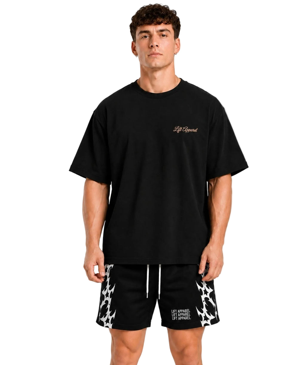 Man wearing a black Pressure oversized gym tee with patterned training shorts, front view