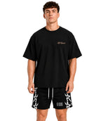 Man wearing a black Pressure oversized gym tee with patterned training shorts, front view