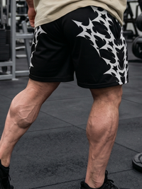 Person wearing black shorts with white patterns in a gym setting
