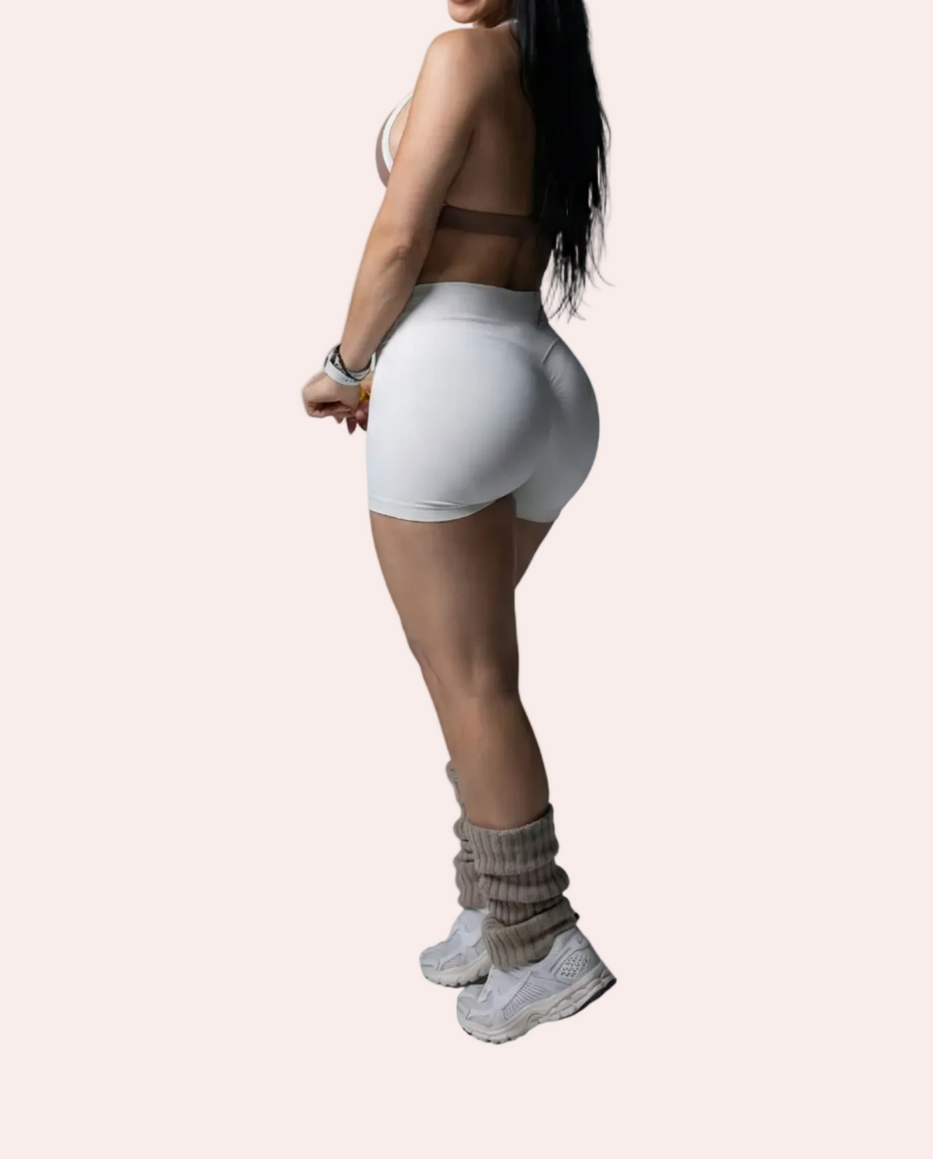 Woman in white athletic wear standing against a gray background